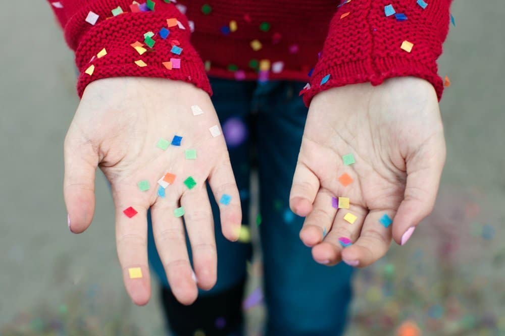 A woman with a red sweater catching confetti in her hands.