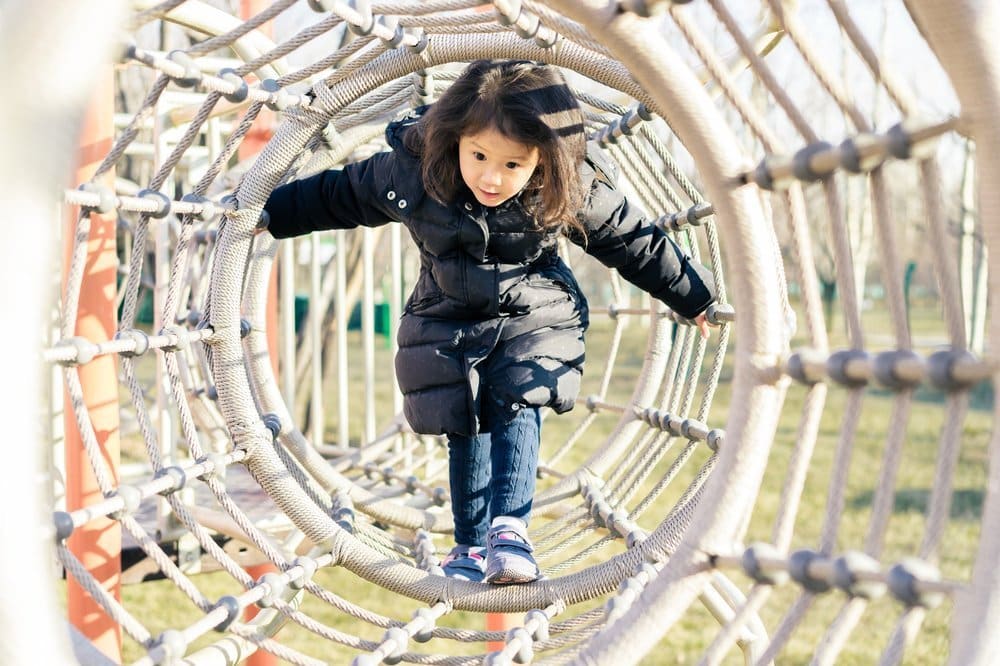 Girl playing on tightrope in playground.