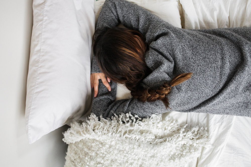 A woman sleeping in bed on her stomach.