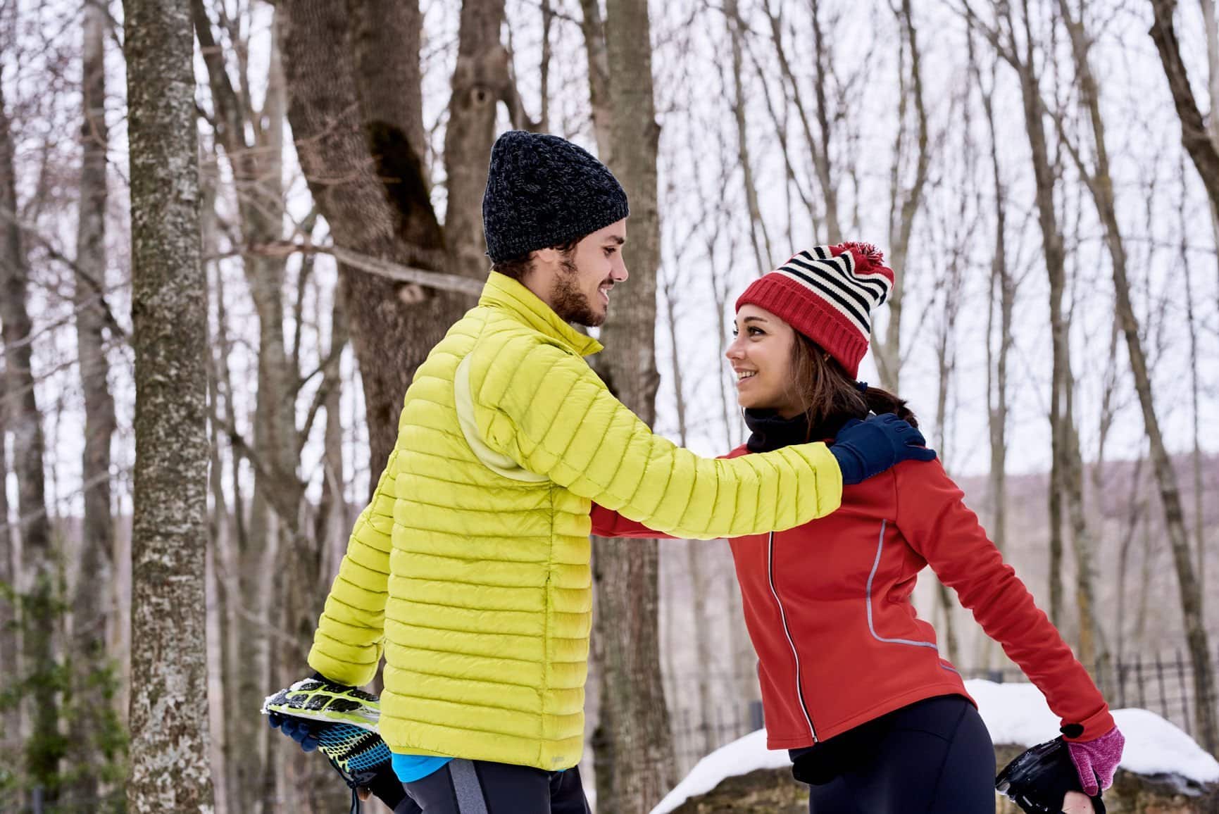 A man and a woman stretching after a workout in the snow.