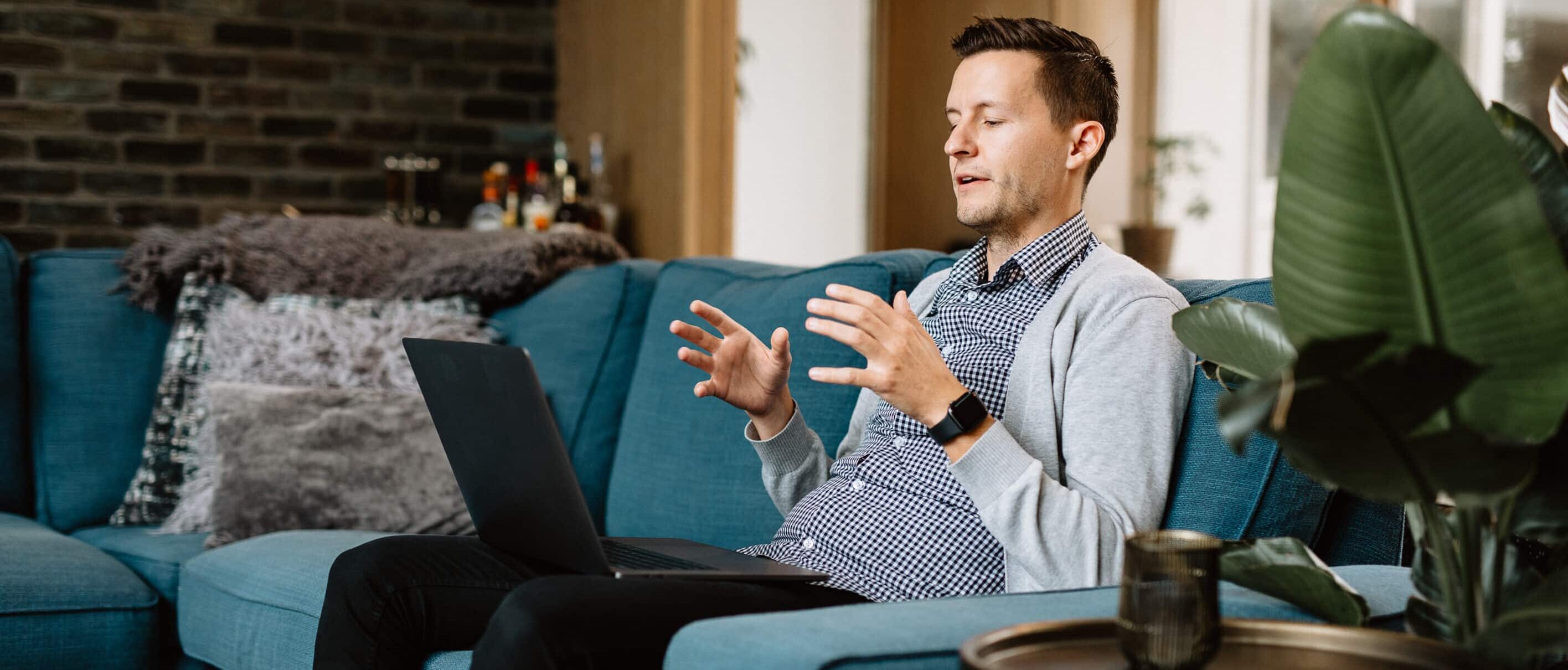 A man sitting on a teal couch in the middle of virtual therapy.