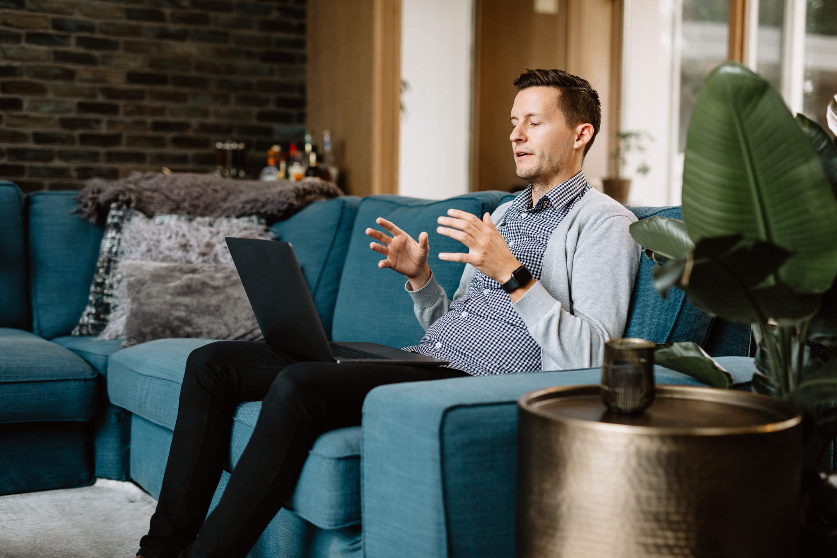 A man sitting on a teal couch in the middle of virtual therapy.