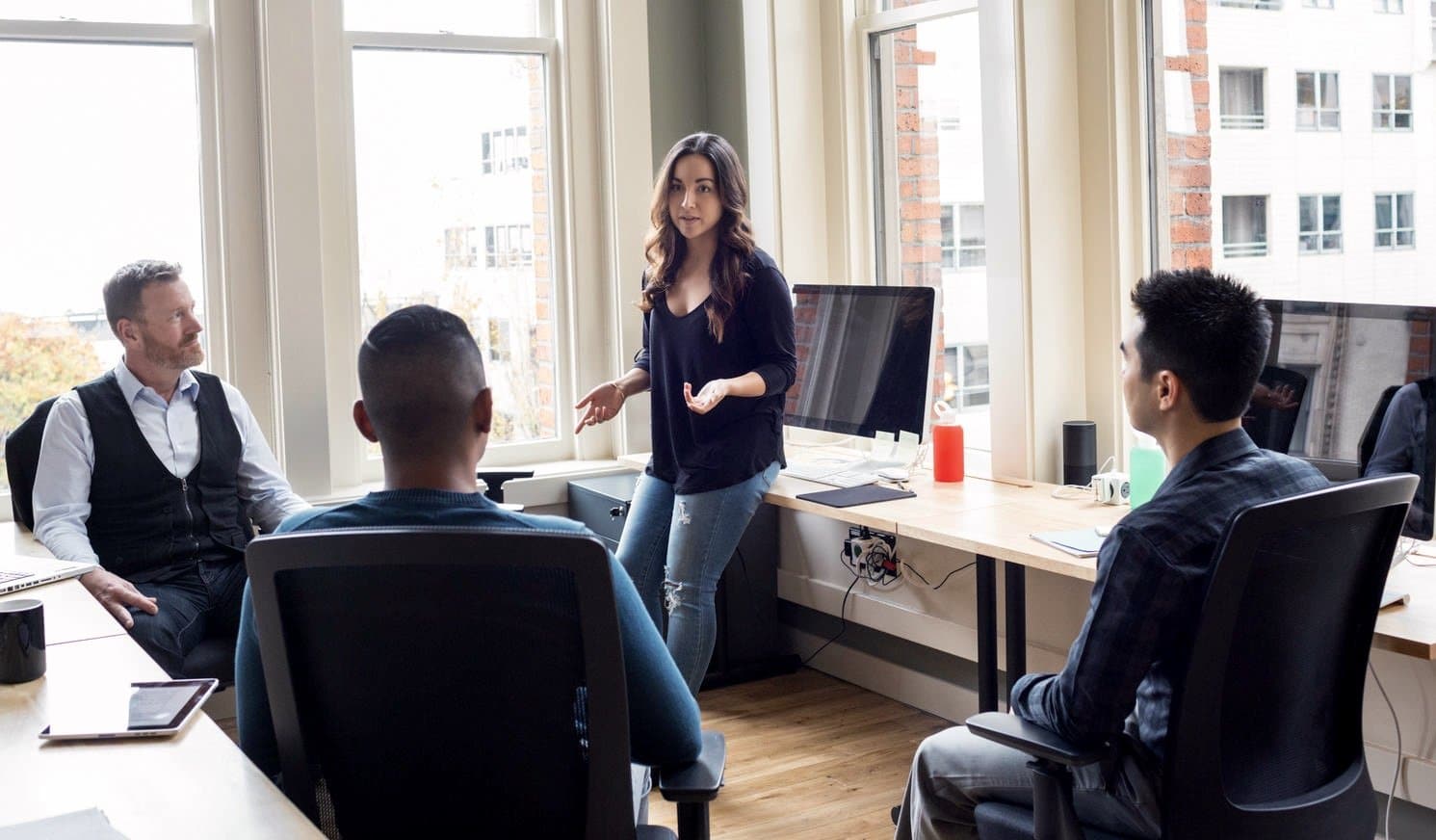 A mixed race group of business people working together in an office full of computers in a shared office space facility.