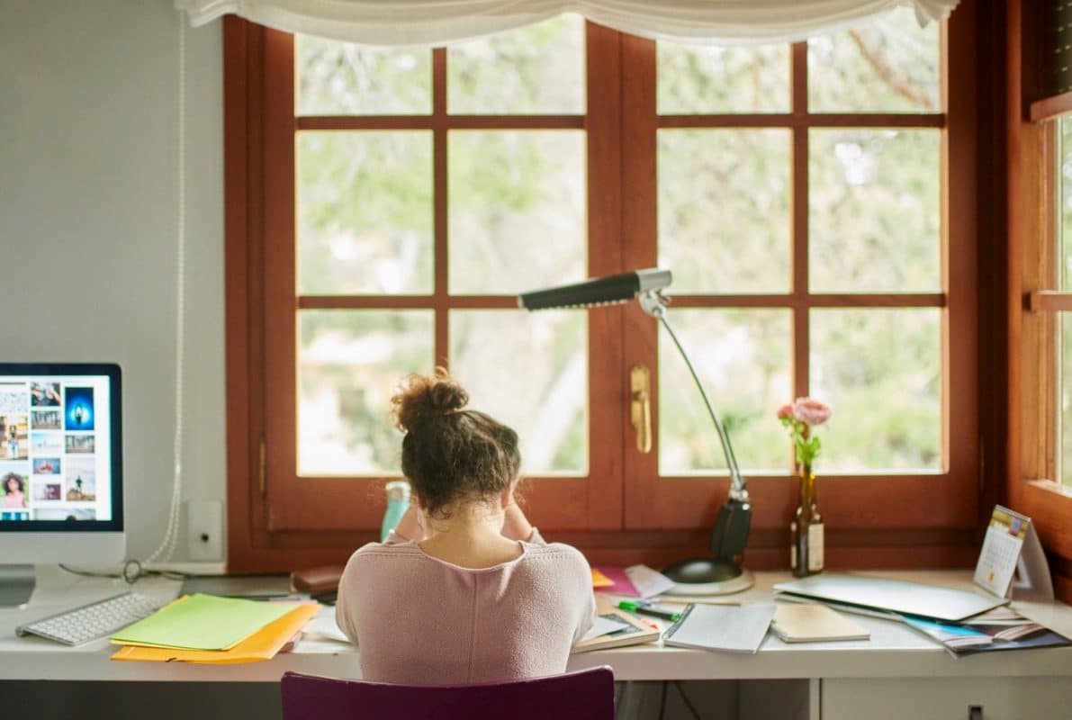 Woman with her head in her arms as she sits at a desk looking upset.