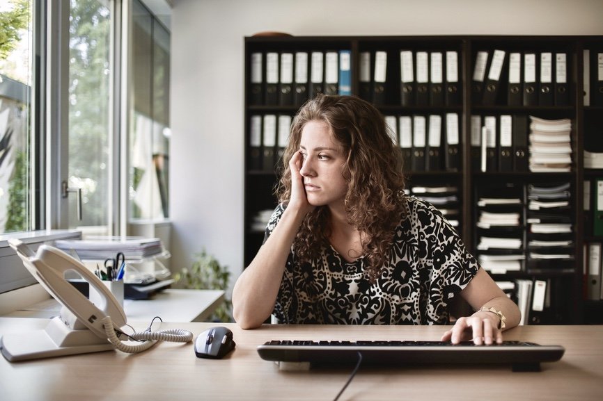 Upset Girl Sitting In Front Of The Computer In Her Office Looking Out Of The Window.