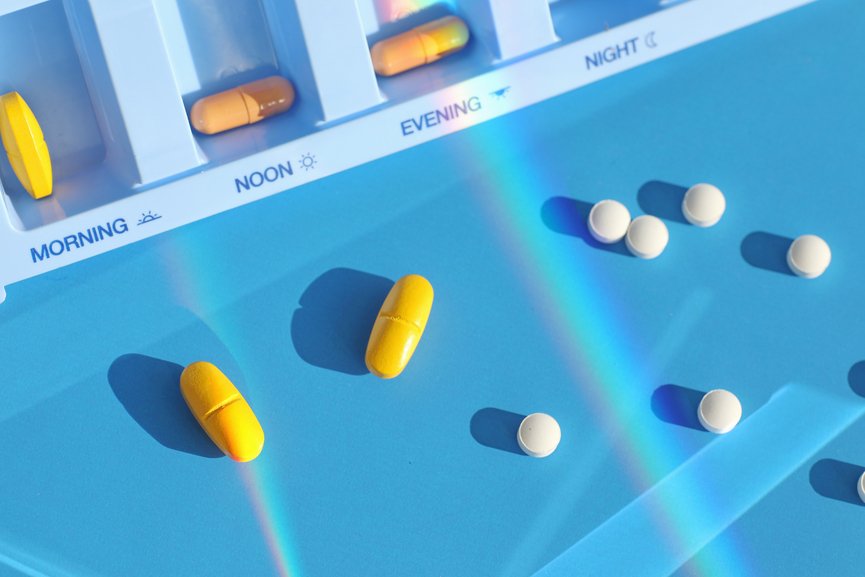 Graphic of a pill box with bright yellow and white pills over a blue background.