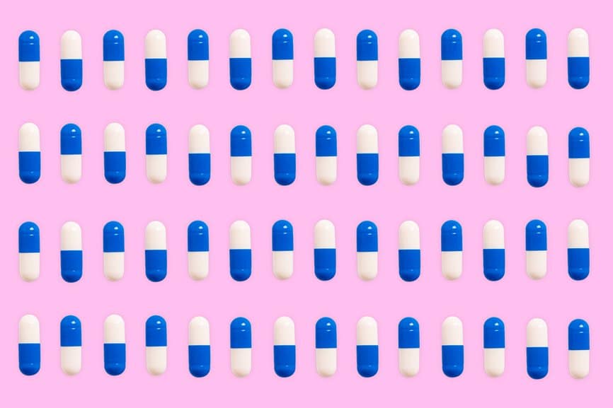 Blue and white pills pattern on a pink background.