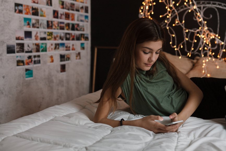 Teenage girl using mobile phone in her bedroom