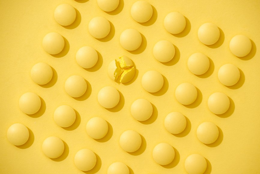 Bright yellow pills in a row on yellow background.