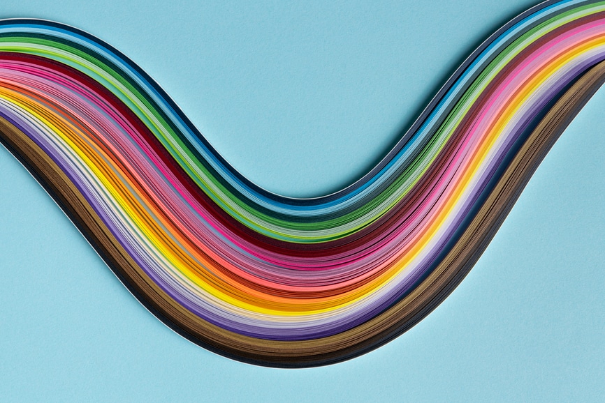 Still life shot of multi colored quilling paper lying on top of colorful paper