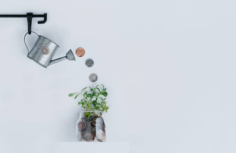 Watering can pouring coins into a jar with money