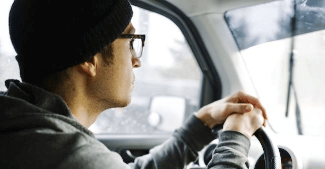 Man wearing a hat driving.