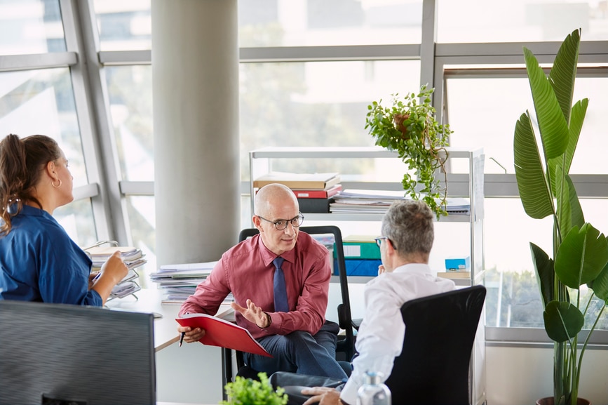 Three co-workers discussing project in office.