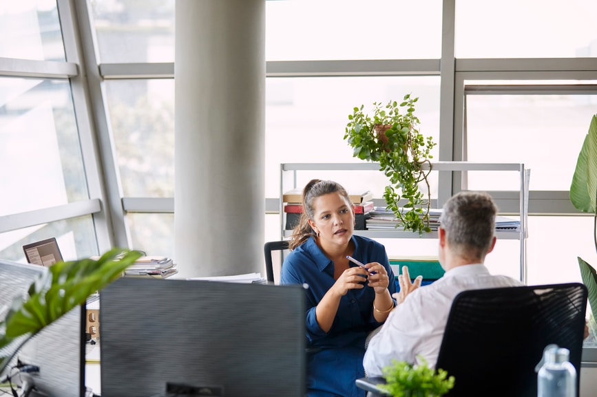 Two co-workers discussing project in office.