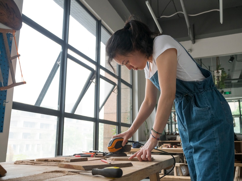 Female Carpenter polish the Chopping board in studio by hand.