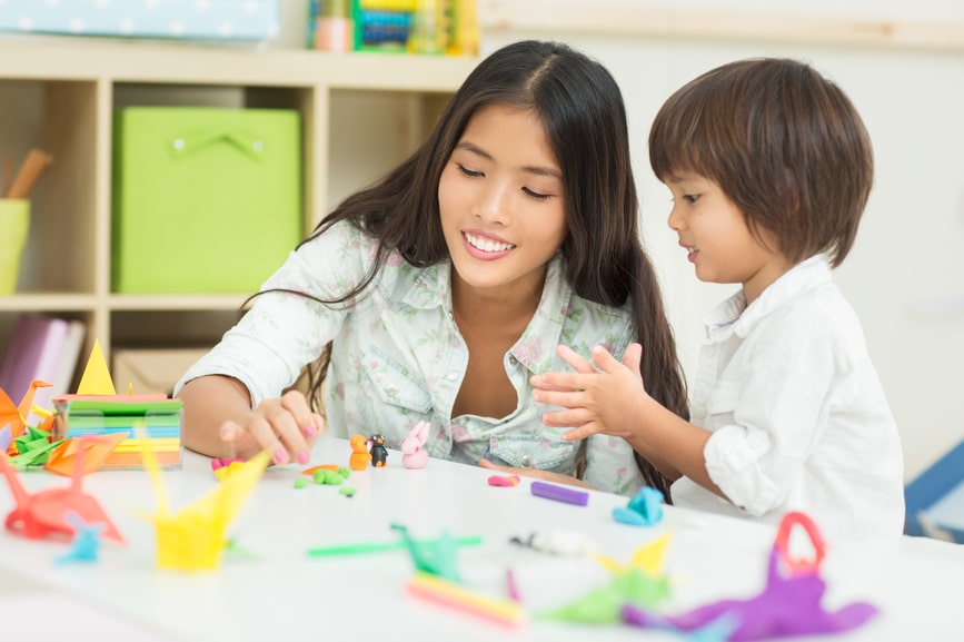 Kindergarten educator and her student making plasticine animals together.