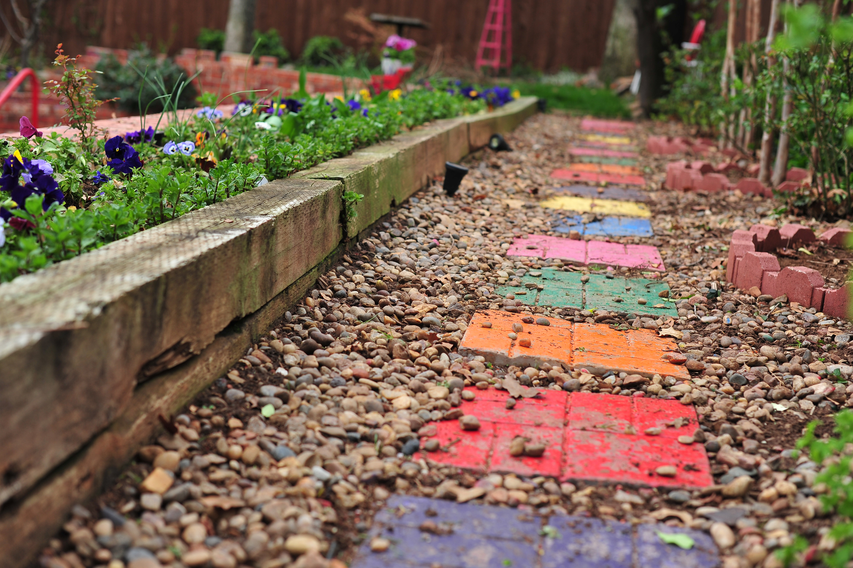 Colorful stepping stones in a gravel pathway leading through a garden.