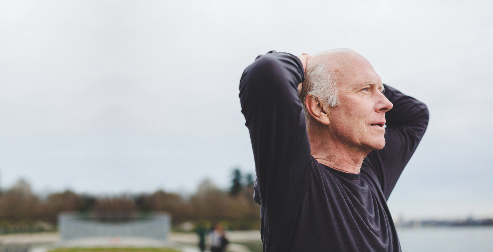 older caucasian male with his hands on his head looking out into the distance