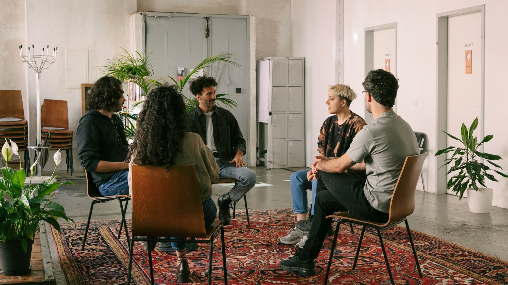 Five multiethnic people sitting on chairs and forming a circle for an introductory sharing circle