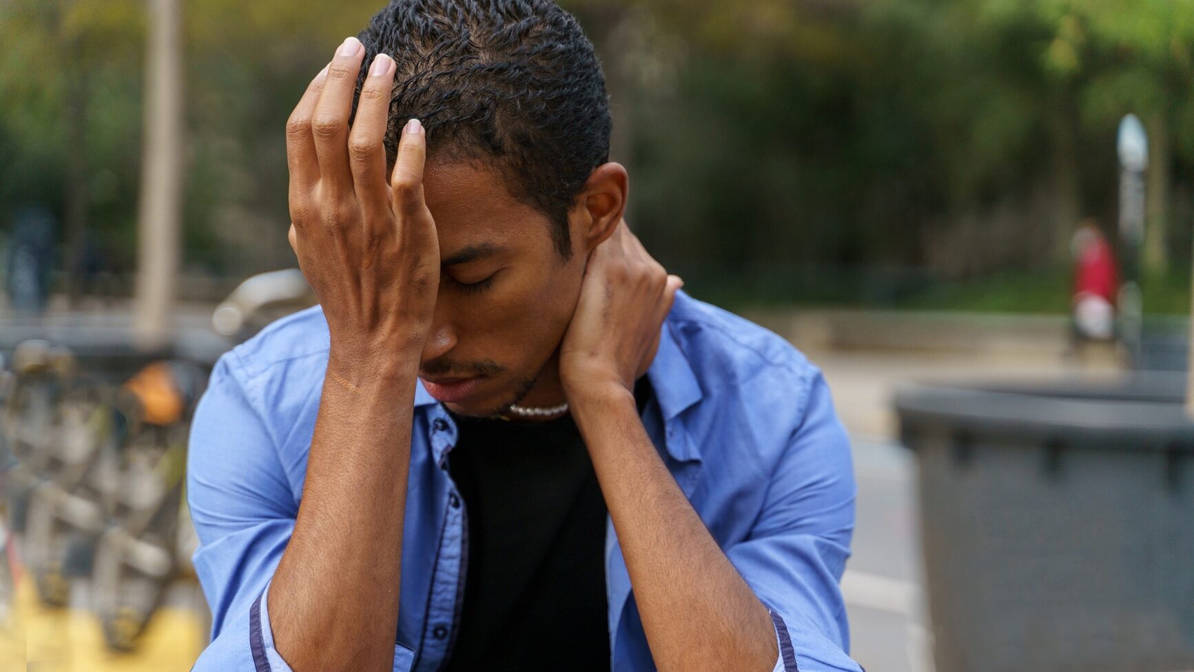 Portrait of young man sitting on bench in the city in urban area during daytime