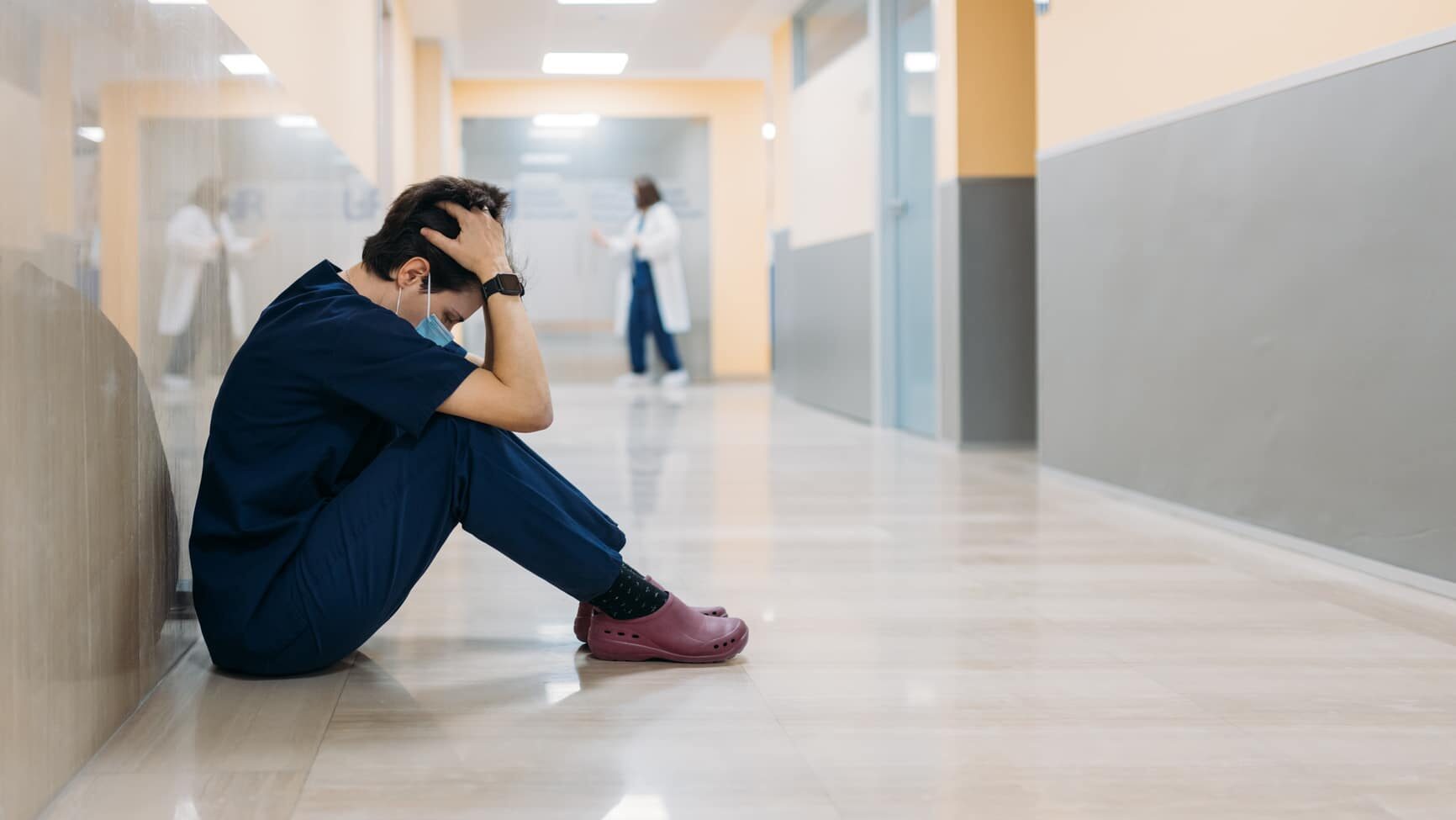 Doctor sitting in the corridor of a hospital tired and sad after a hard day at work