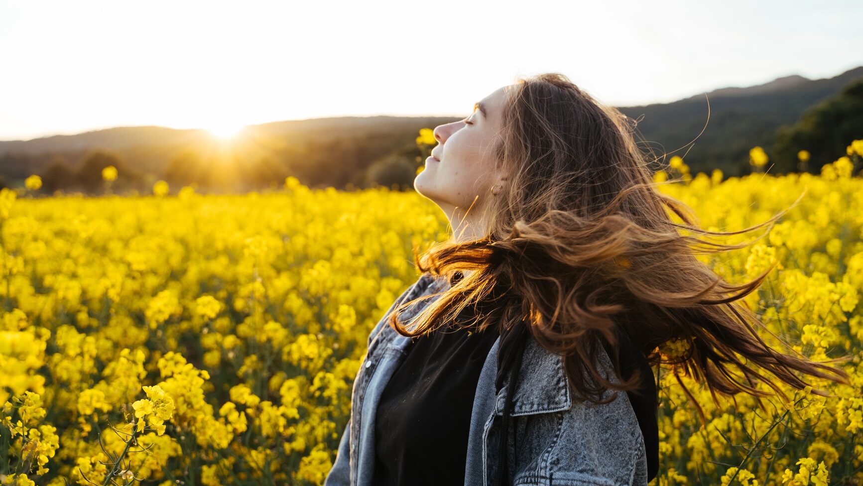 Happy young woman in buckwheat flowers field during sunset having fun and feeling free