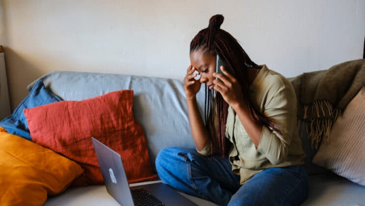woman with braided hair sitting on couch at home living room.