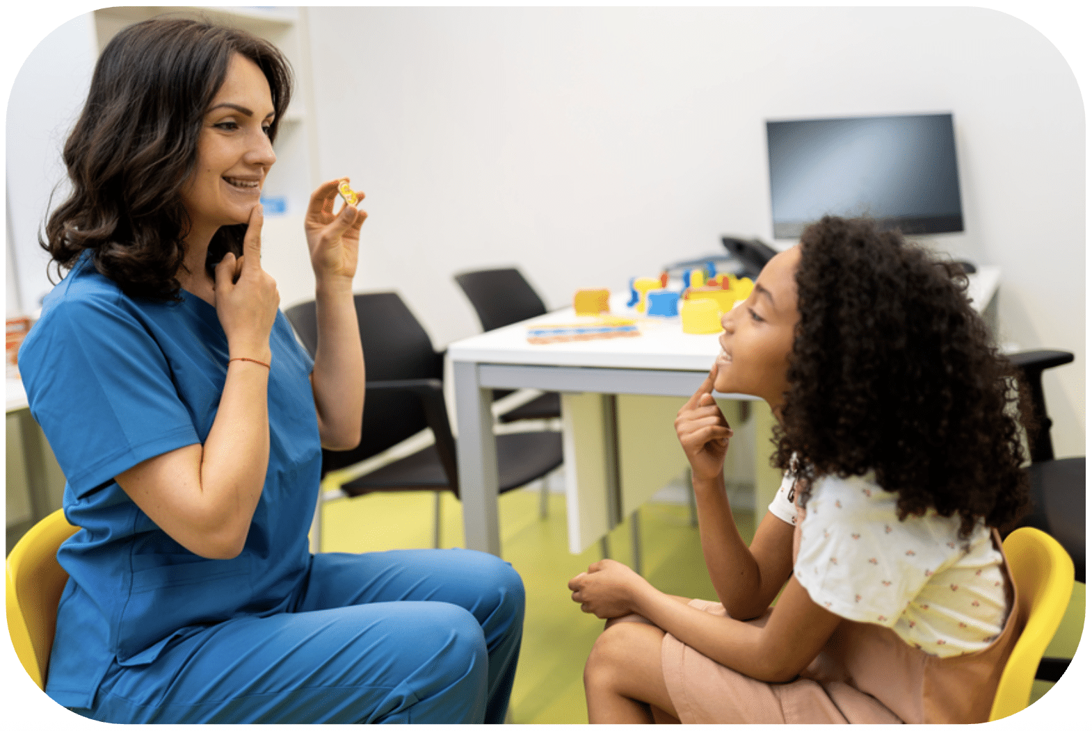 Speech therapist teaching good pronunciation trough games to a child. They are in the doctor's office.
