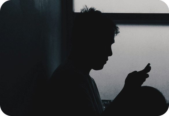 photo of a man on his phone in the dark