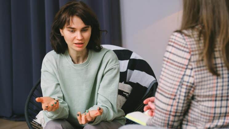 woman sitting on couch talking to another woman