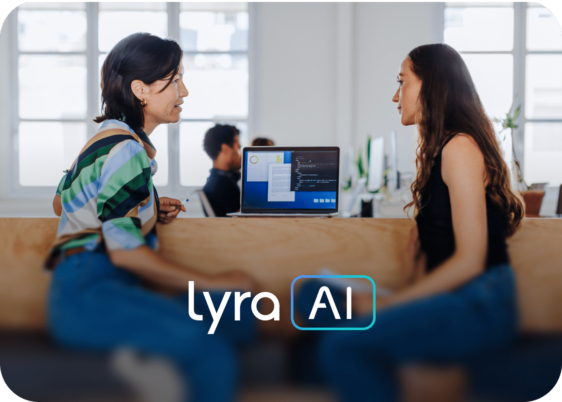 Two women sit and talk in a bright office with a laptop between them. The laptop screen displays code, and the words lyra AI are overlaid on the image. Two other people work in the background.