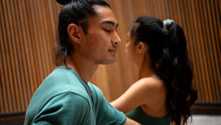 Closeup of young man and woman practicing seated twist yoga pose together