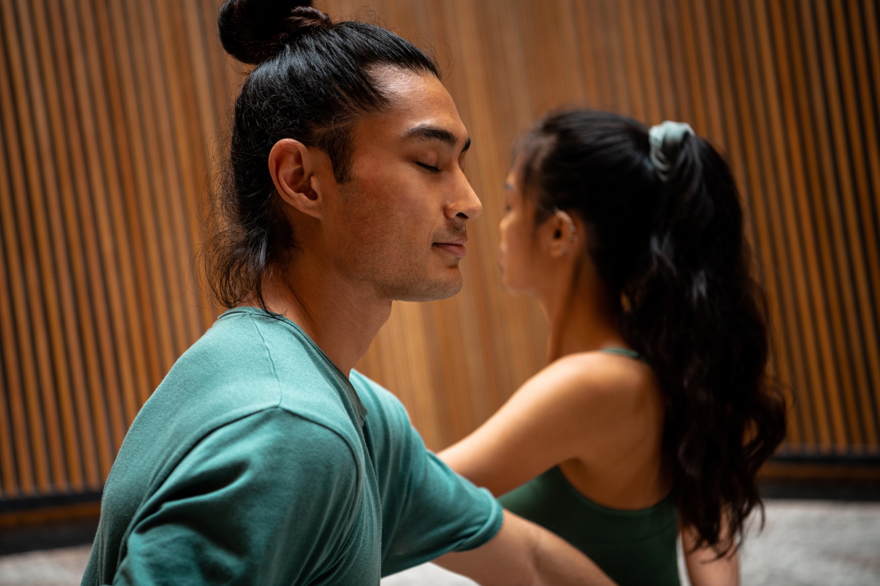 Closeup of young man and woman practicing seated twist yoga pose together